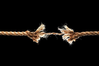 Taut rope breaking apart isolated over a black background